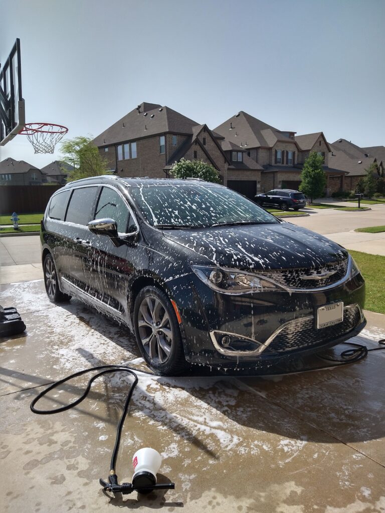 An SUV covered in thick white foam during a professional detailing wash.